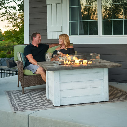 Outdoor GreatRoom Alcott ALC-1224 in a manufacturer porch installation, showing the tabletop, whitewashed base and optional glass wind guard; wind guard, furniture and surroundings are not included