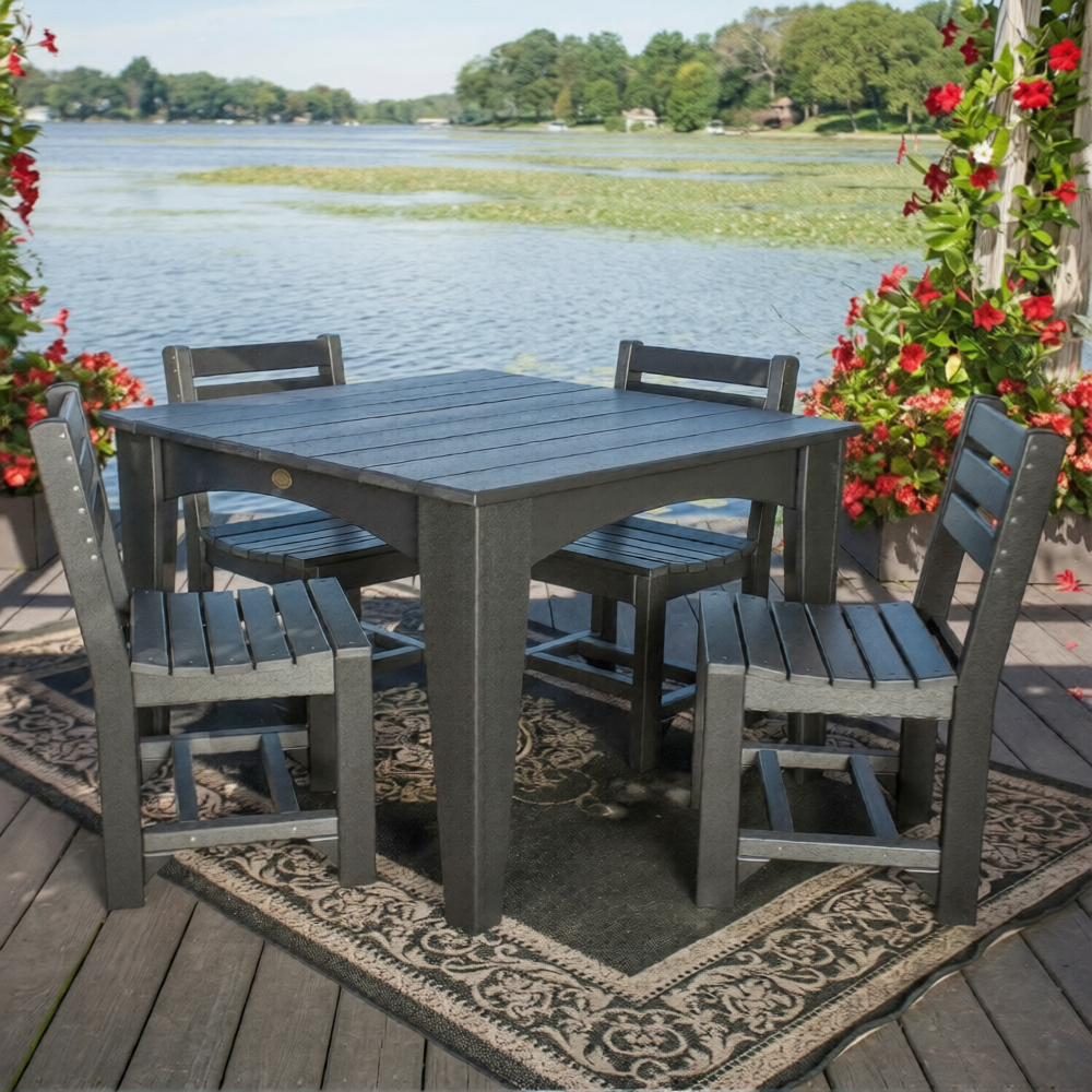 Outdoor dining set with table and  four chairs on a deck by a lake